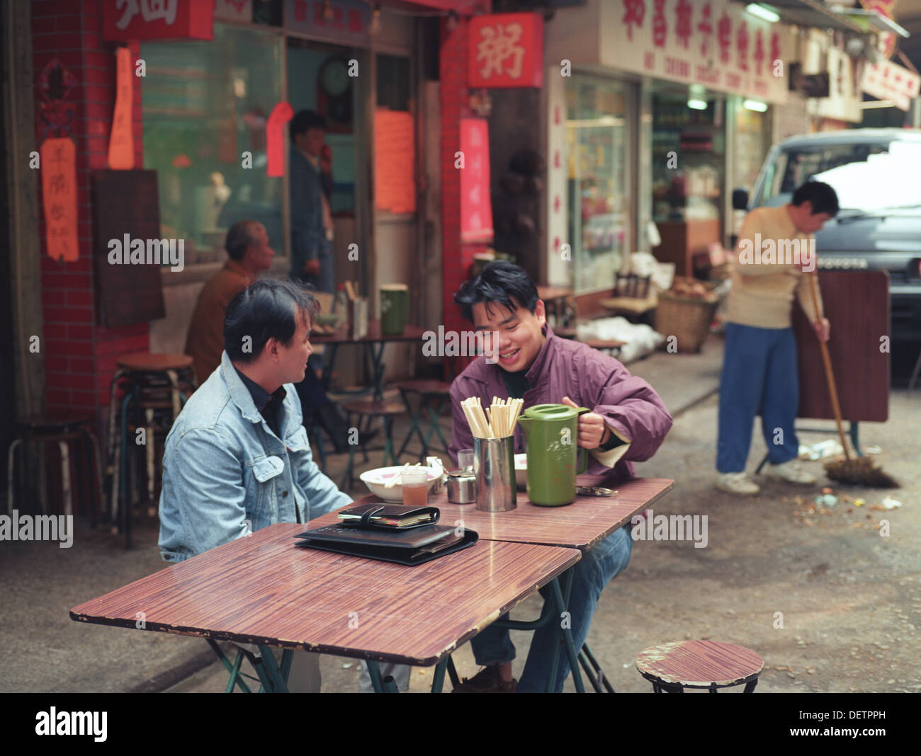 Deux hommes assis dehors à une table de manger des aliments à Hong Kong Banque D'Images