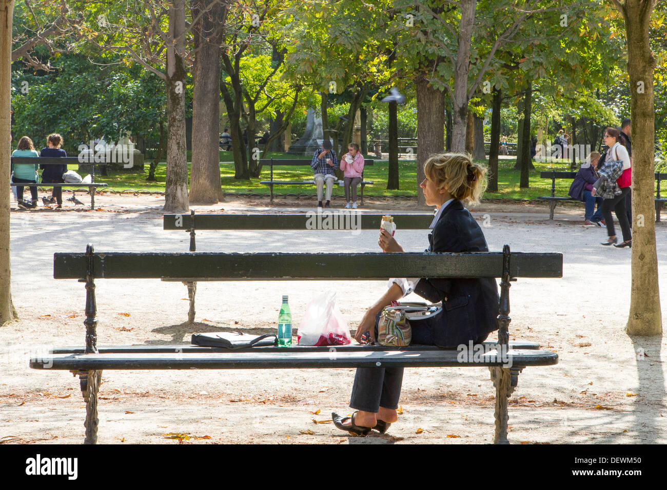 jeune femme assise seule sur le banc du parc pour déjeuner Banque D'Images