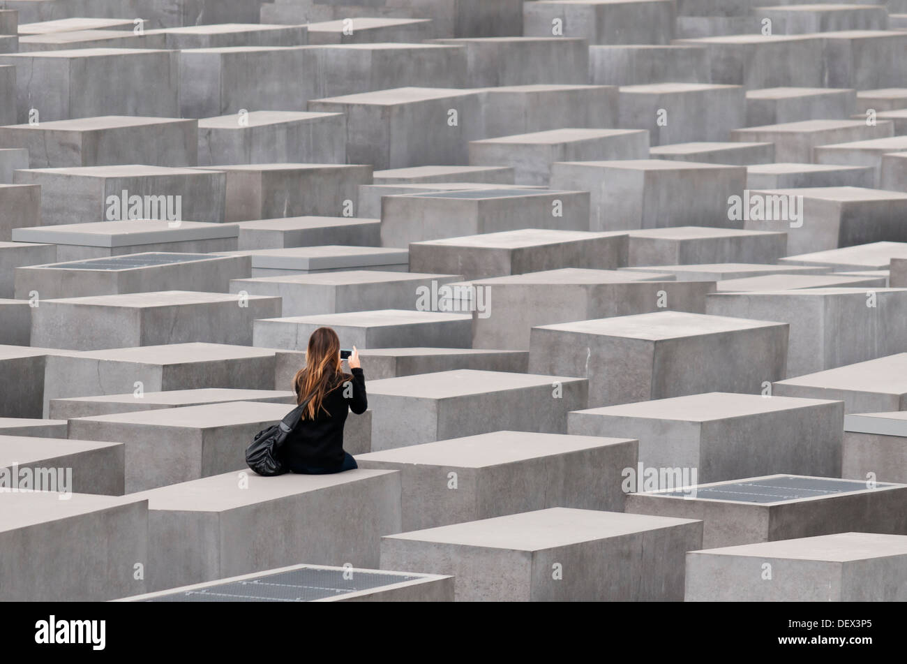 Jeune femme parmi les stèles de béton du Mémorial aux Juifs assassinés d'Europe (Holocaust Memorial), Berlin, Allemagne Banque D'Images