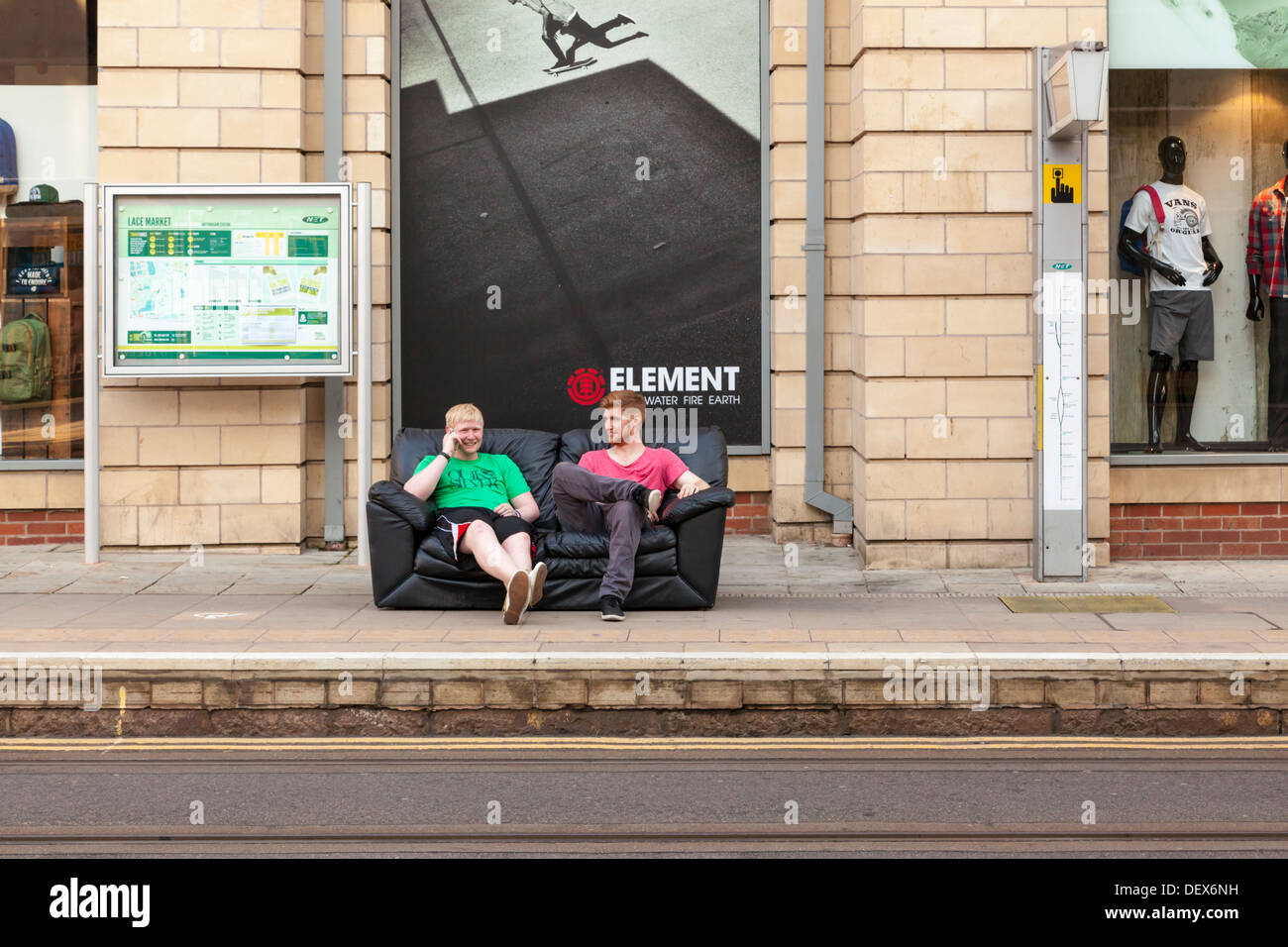 Deux jeunes hommes assis sur un canapé en attente d'un tram dans le centre-ville de Nottingham, Angleterre, RU Banque D'Images