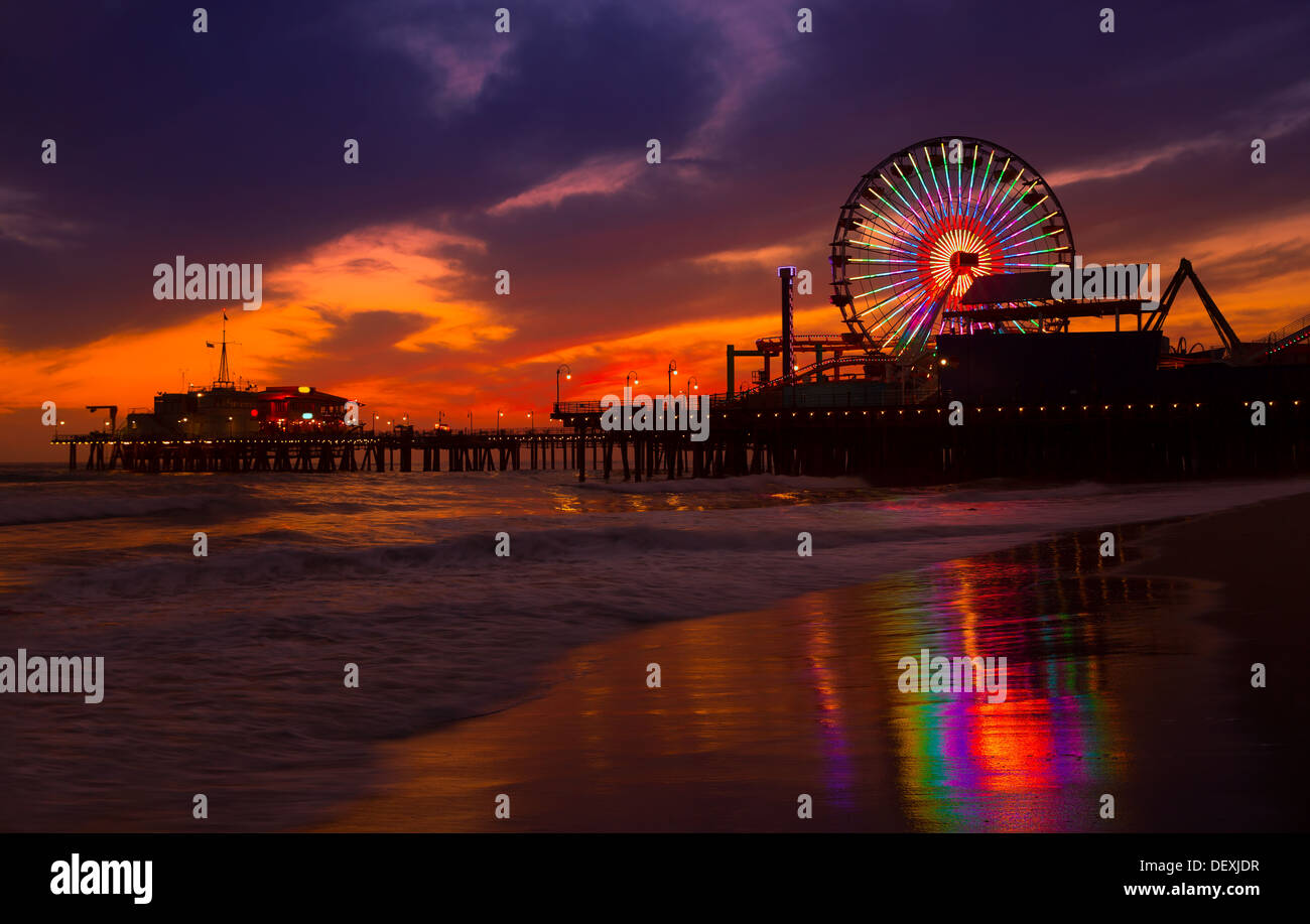 Santa Monica California Sunset sur Pier Ferrys et la réflexion sur des roues sur le sable mouillé de la plage Banque D'Images