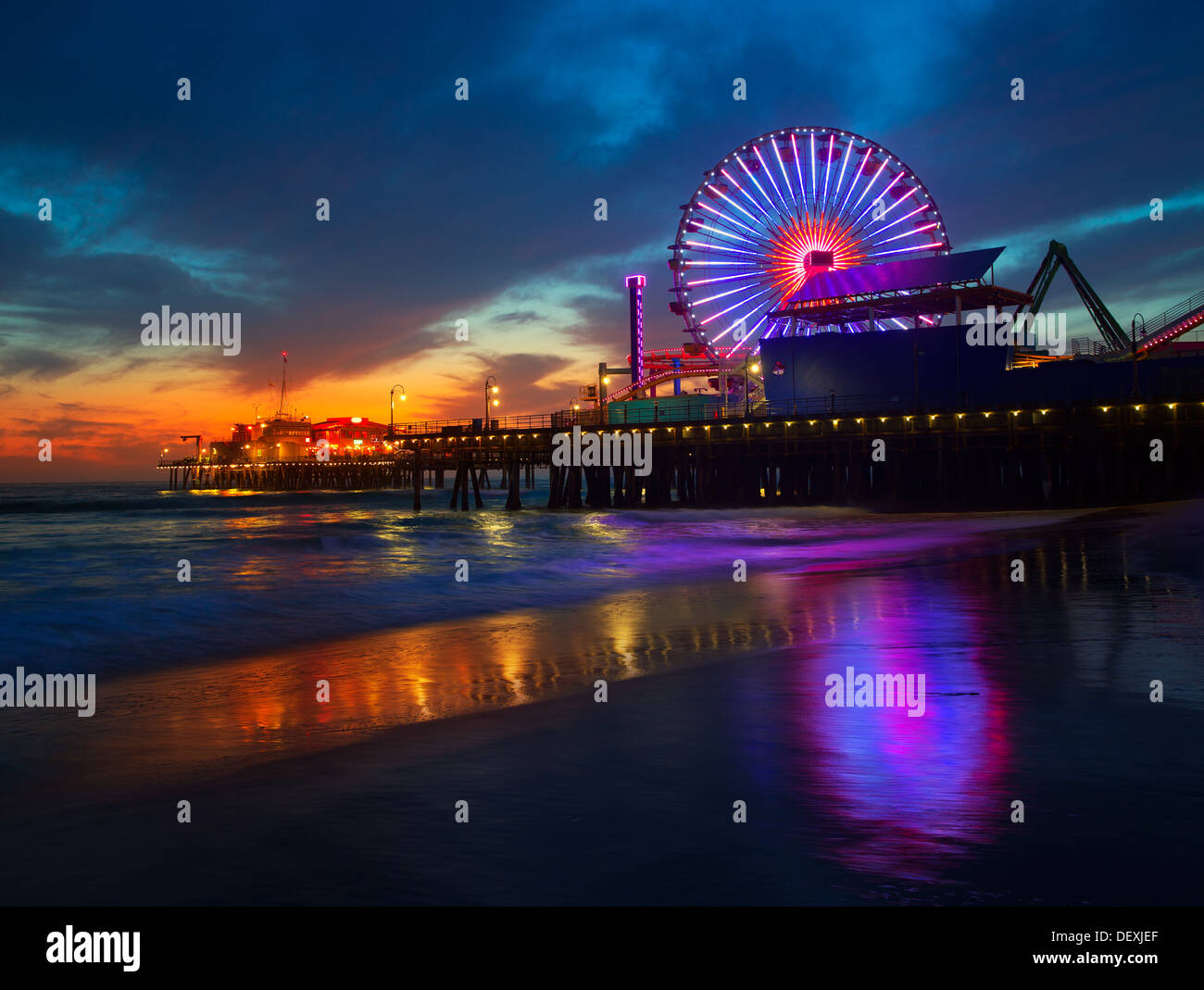 Santa Monica California Sunset sur Pier Ferrys et la réflexion sur des roues sur le sable mouillé de la plage Banque D'Images