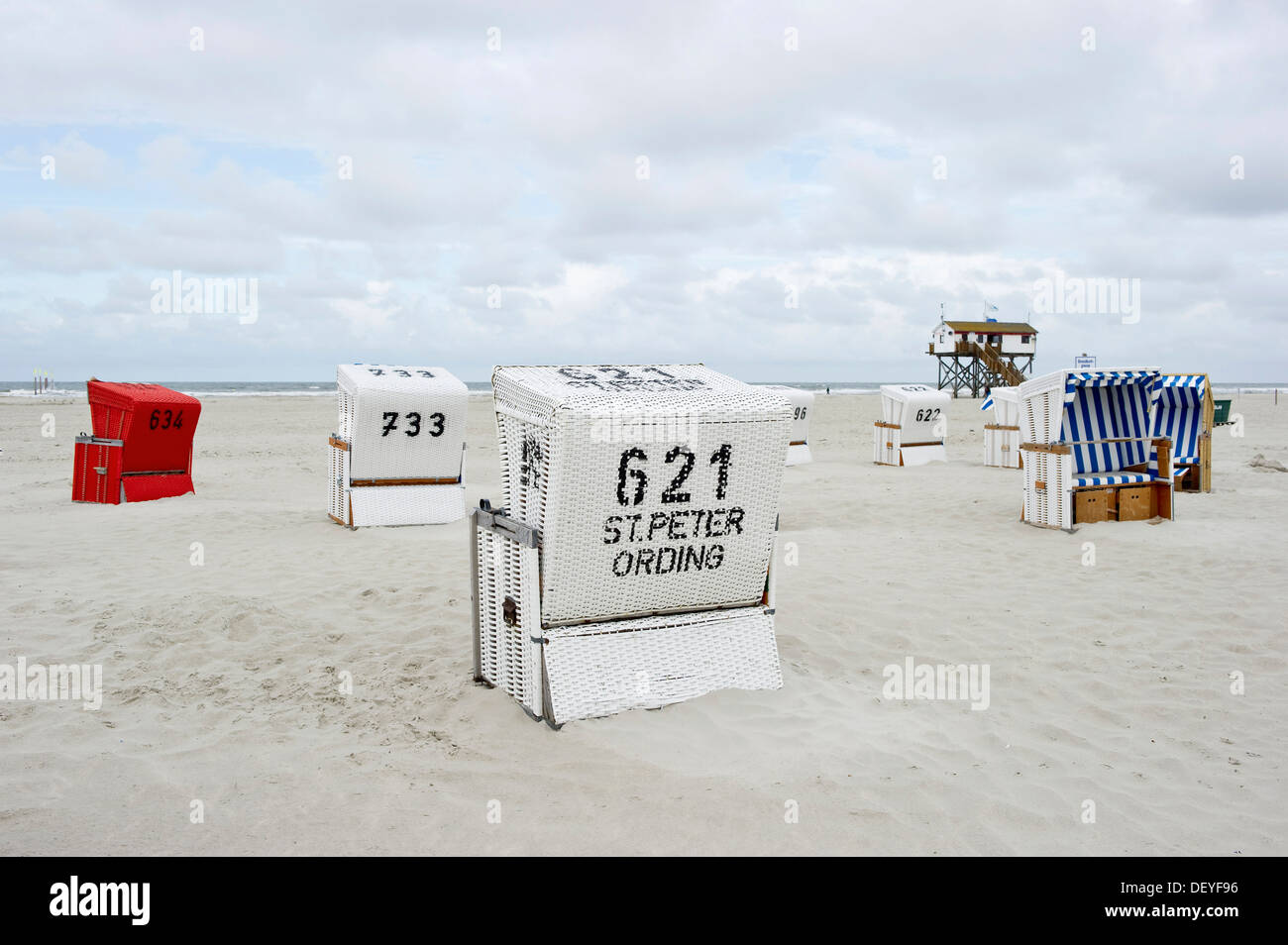 Chaises de plage en osier couvert sur la plage en face d'une maison sur pilotis, St Peter-Ording, Schleswig-Holstein, Allemagne Banque D'Images