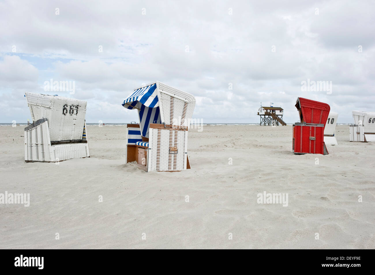 Chaises de plage en osier couvert sur la plage en face d'une maison sur pilotis, St Peter-Ording, Schleswig-Holstein, Allemagne Banque D'Images