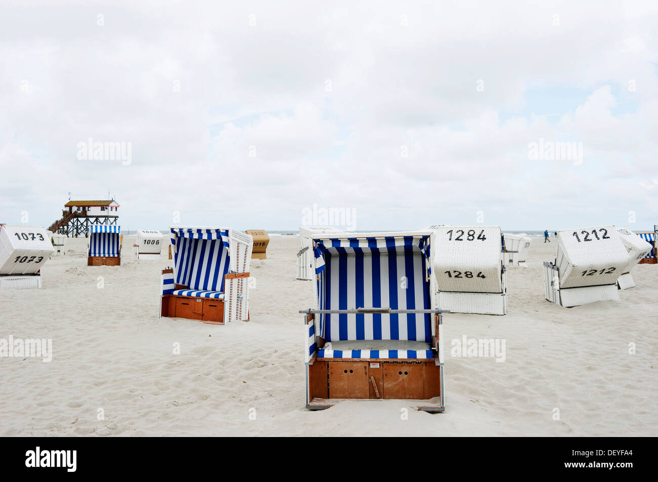 Chaises de plage en osier couvert sur la plage en face d'une maison sur pilotis, St Peter-Ording, Schleswig-Holstein, Allemagne Banque D'Images