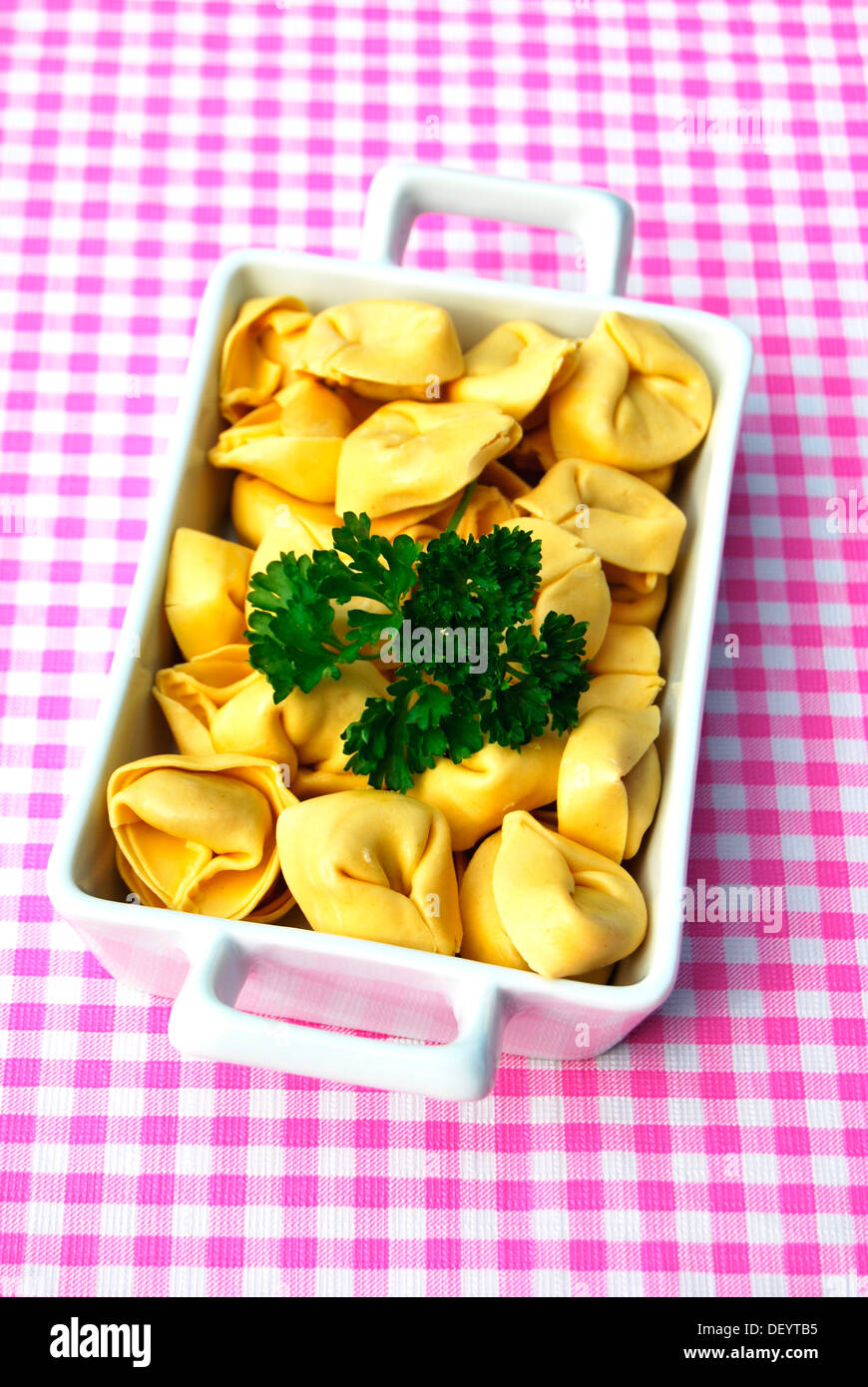 Tortellini dans un plat allant au four, servi avec du persil, nappe à carreaux Banque D'Images