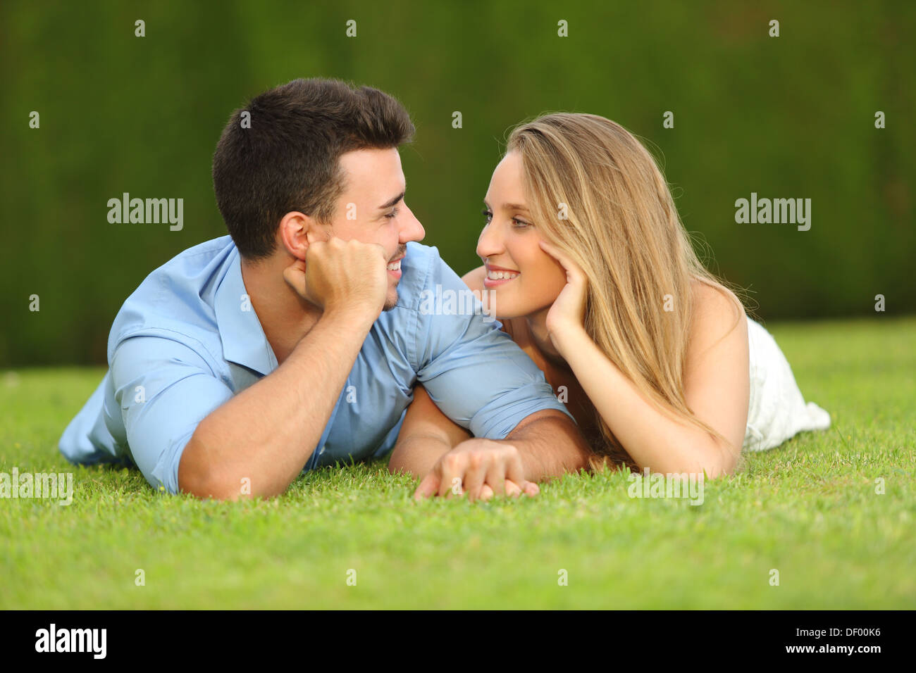 Couple in love dating et à chaque autre couché dans l'herbe avec un fond vert Banque D'Images