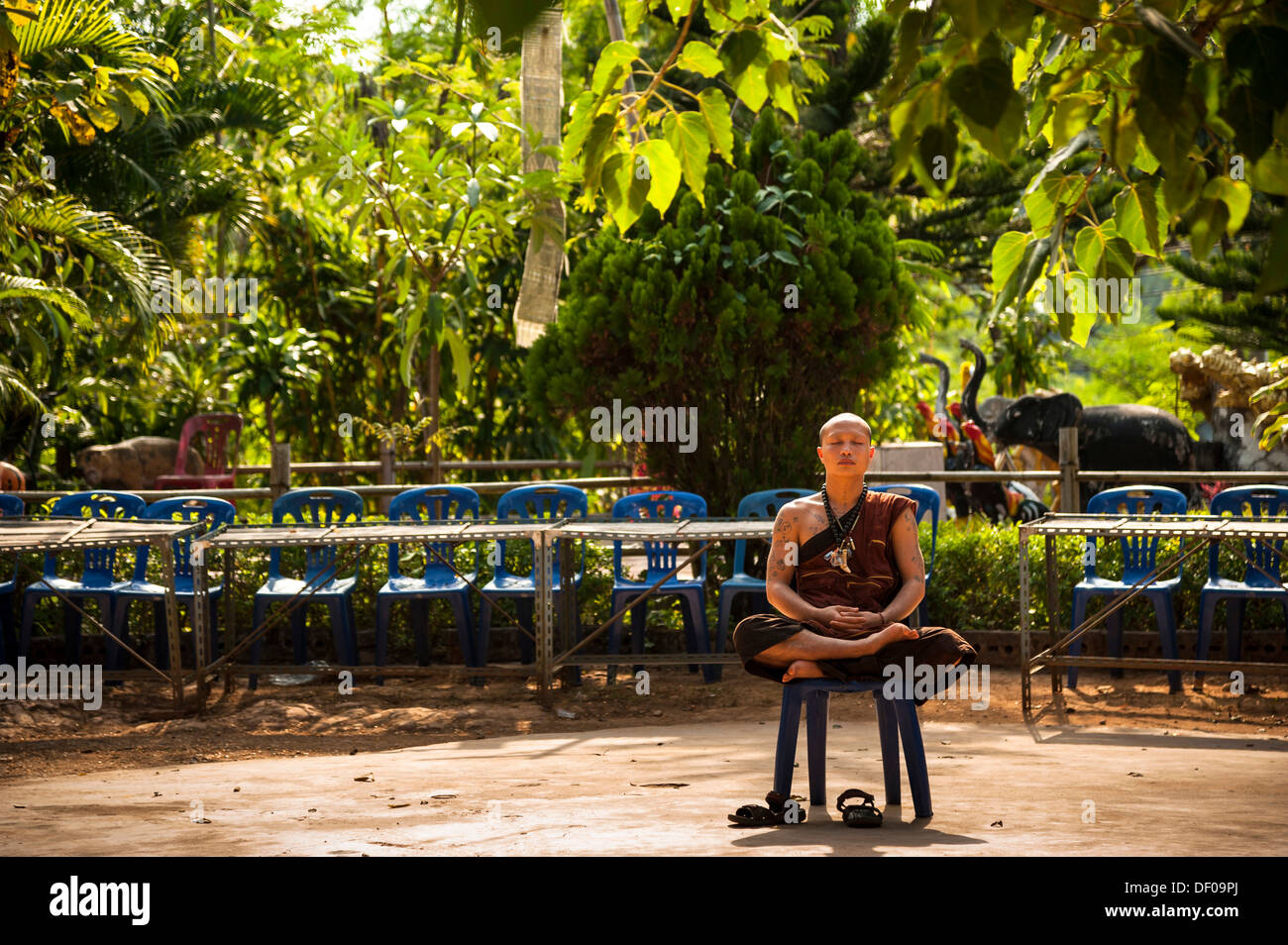 Prier ou méditer moine assis sur une chaise en plastique, temple et monastère de Wat Phra Thong Archa ou Golden Horse Banque D'Images