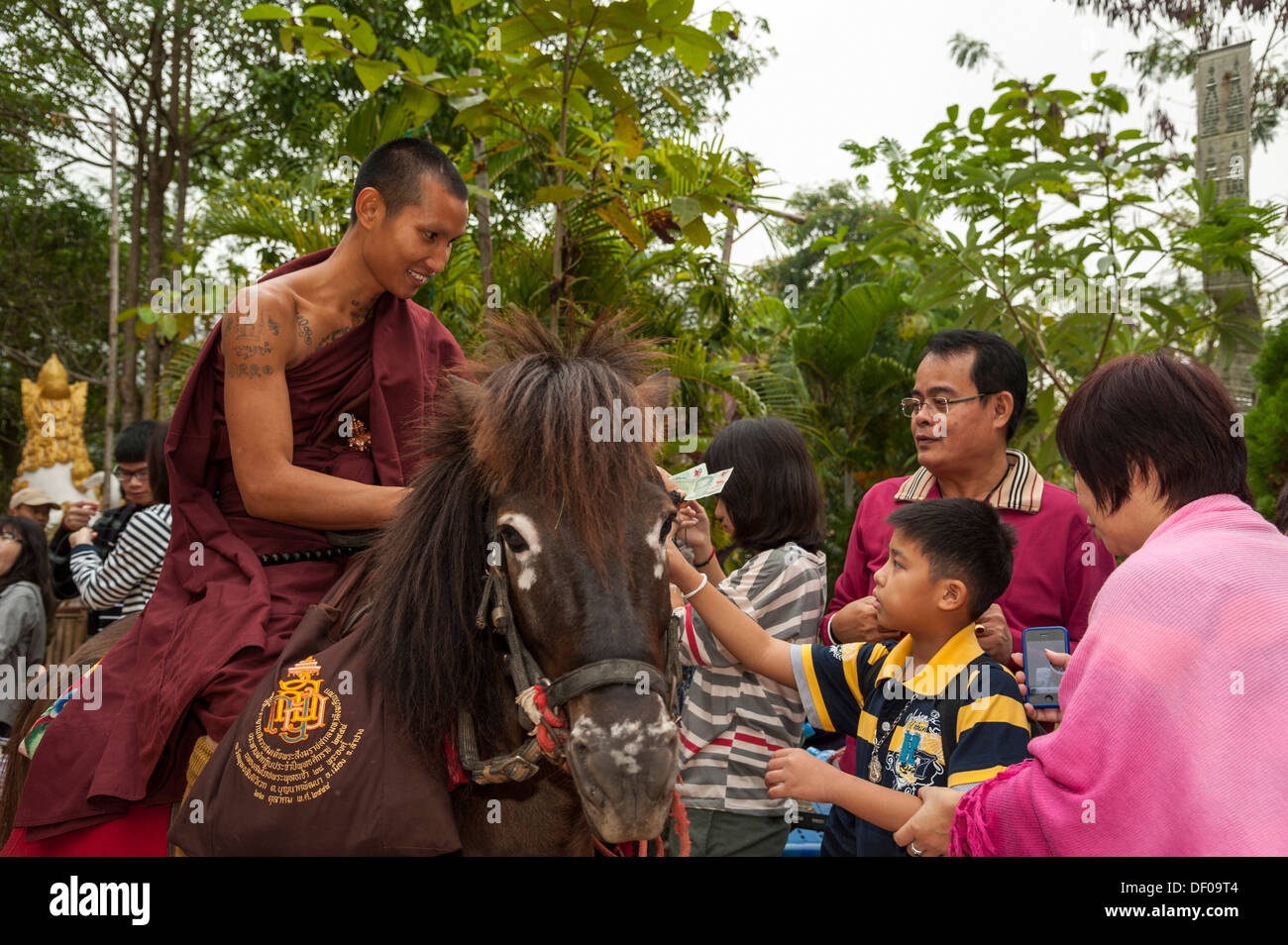 Le moine bouddhiste à cheval la collecte des aumônes au matin, temple et monastère de Wat Phra Thong Archa ou Temple du Cheval d'Or Banque D'Images