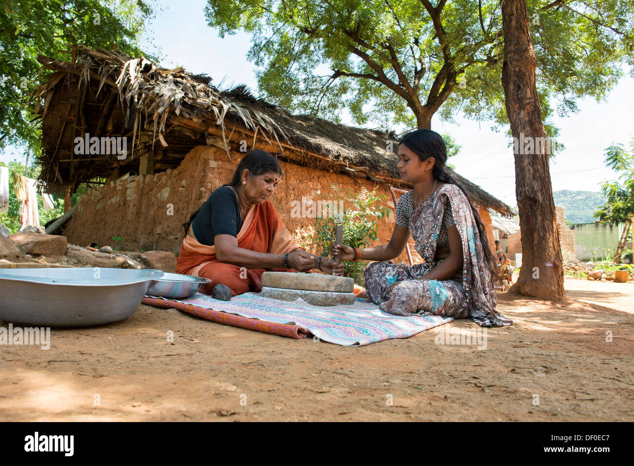 Les femmes village à l'aide de meules pierres pour moudre le mil rouge / Graines Graines Ragi Ragi en farine. L'Andhra Pradesh. L'Inde Banque D'Images