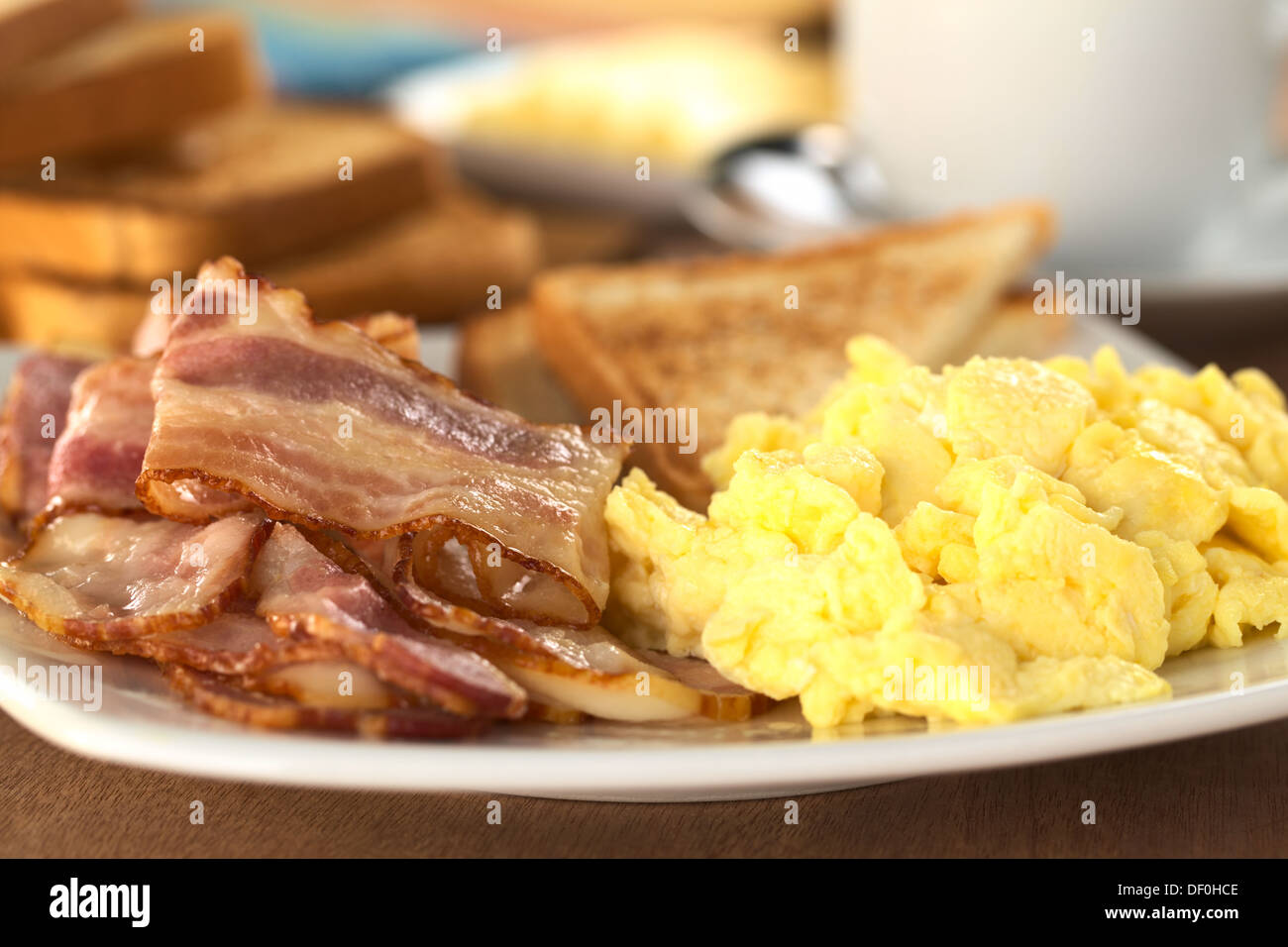 Fried bacon et œufs brouillés avec des toasts de pain à l'arrière (Selective Focus, Focus sur le bord inférieur de l'bacon sur le dessus) Banque D'Images