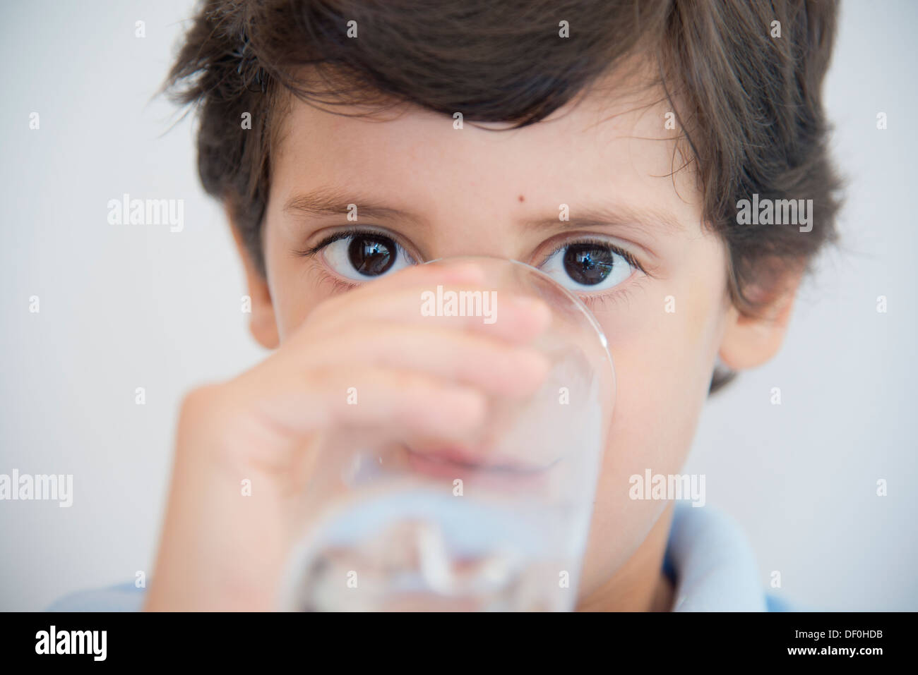 Face close up d'un garçon en bleu clair verre d'eau potable Banque D'Images
