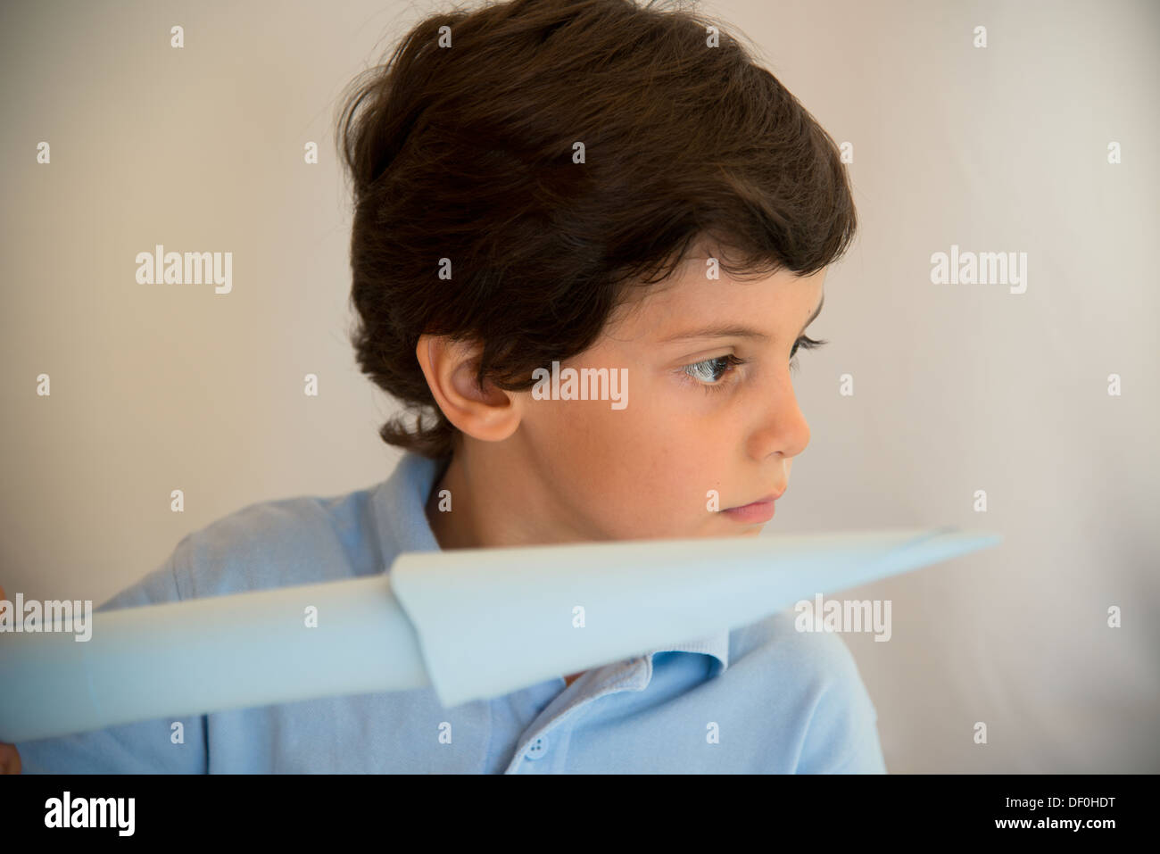 A boy holding en papier tous les avions en bleu clair Banque D'Images