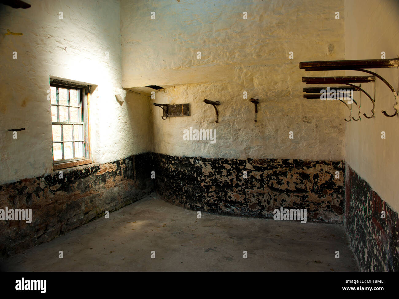 Anciennes écuries à l'intérieur de bâtiment historique avec la lumière de la fenêtre et les supports sur les murs Banque D'Images