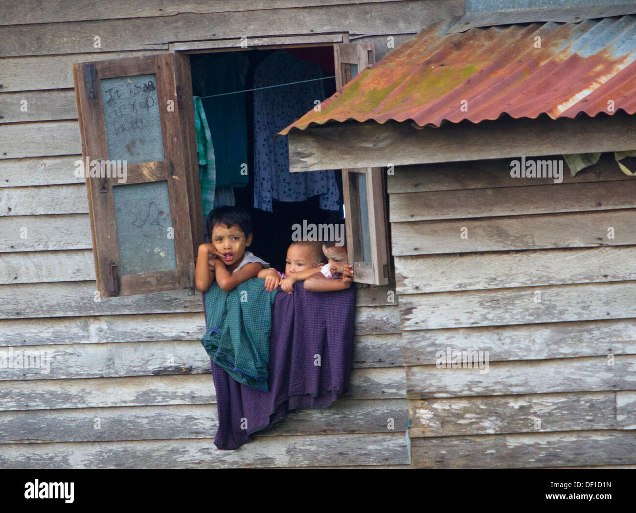 Les enfants de regarder par une fenêtre à l'extérieur de Kinpun, Birmanie. Banque D'Images