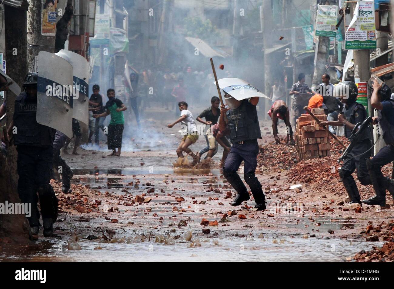 Narayanganj, au Bangladesh. 26 août, 2013. Les fonctionnaires de police du Bangladesh se mettre à couvert, des travailleurs du vêtement jeter des pierres au cours d'une manifestation dans la région de Narayanganj le 26 septembre 2013. La plupart des usines de confection du Bangladesh ont rouvert après cinq jours de manifestations violentes sur les hausses de salaires pour les travailleurs du textile, après que le gouvernement s'est engagé à réprimer les troubles civils 'avec tous vigueur . Banque D'Images