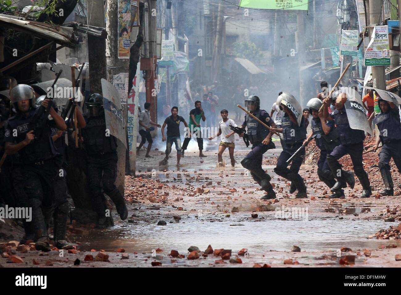 Narayanganj, au Bangladesh. 26 août, 2013. Les fonctionnaires de police du Bangladesh se mettre à couvert, des travailleurs du vêtement jeter des pierres au cours d'une manifestation dans la région de Narayanganj le 26 septembre 2013. La plupart des usines de confection du Bangladesh ont rouvert après cinq jours de manifestations violentes sur les hausses de salaires pour les travailleurs du textile, après que le gouvernement s'est engagé à réprimer les troubles civils 'avec tous vigueur . Banque D'Images