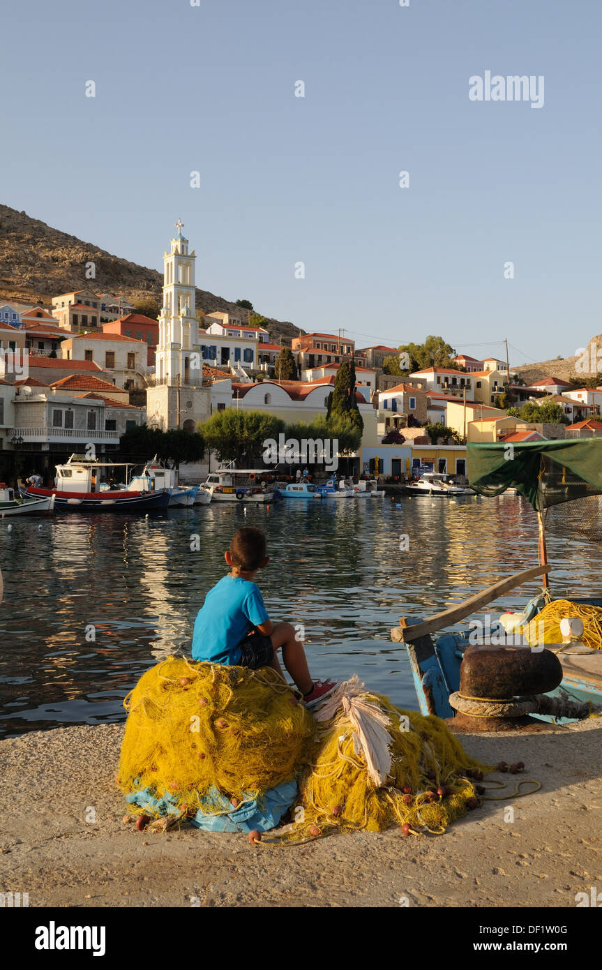 Un petit garçon grec assis sur les filets de pêche Port Halki Chalki Emporio Le Dodécanèse Grèce mer Egéé Banque D'Images