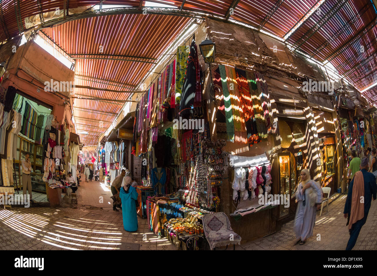 Les toits à lattes illuminant le décrochage, vêtements et les femmes marocaines shopping en costume traditionnel dans un souk local, Marrakech, Maroc Banque D'Images