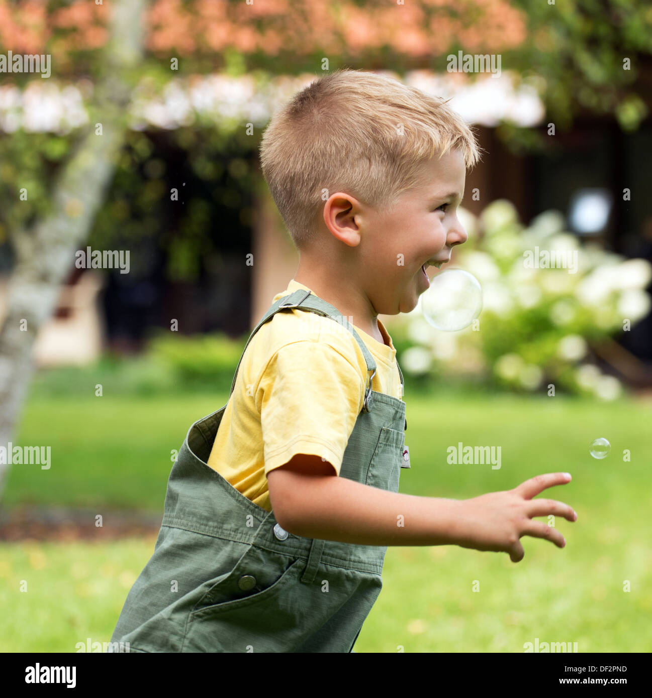 Kid petit mignon chassant les bulles de savon Banque D'Images