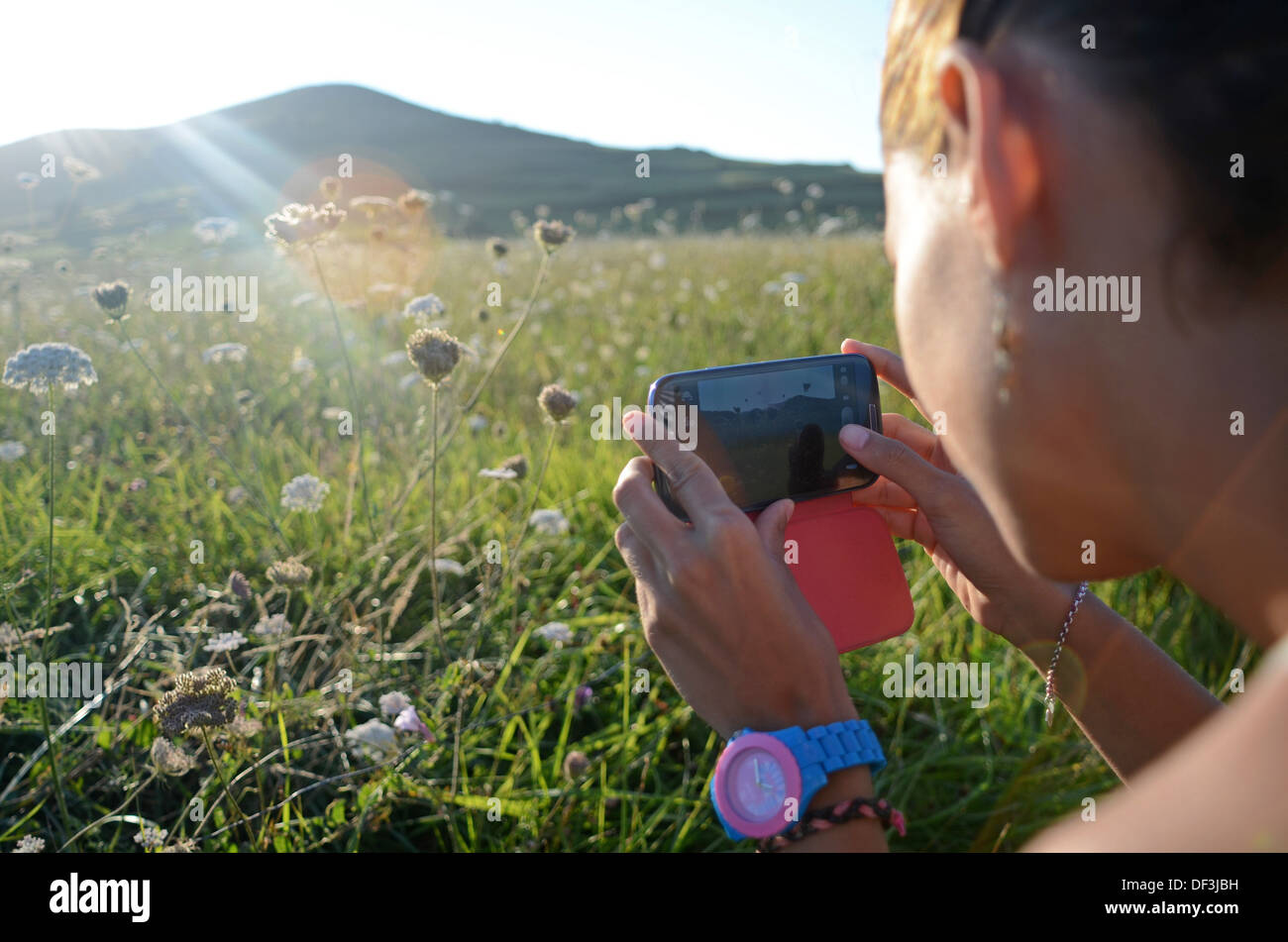 Jeune femme prend des photos de la nature avec son téléphone portable Banque D'Images