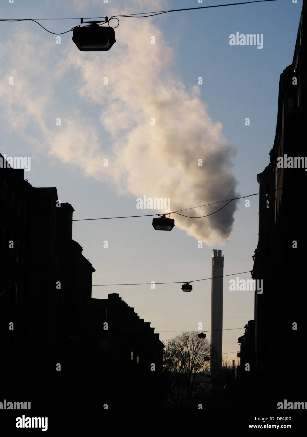 Silhouette de lumières à travers les fils de rue que la fumée s'élève hors de cheminée d'usine en arrière-plan Banque D'Images