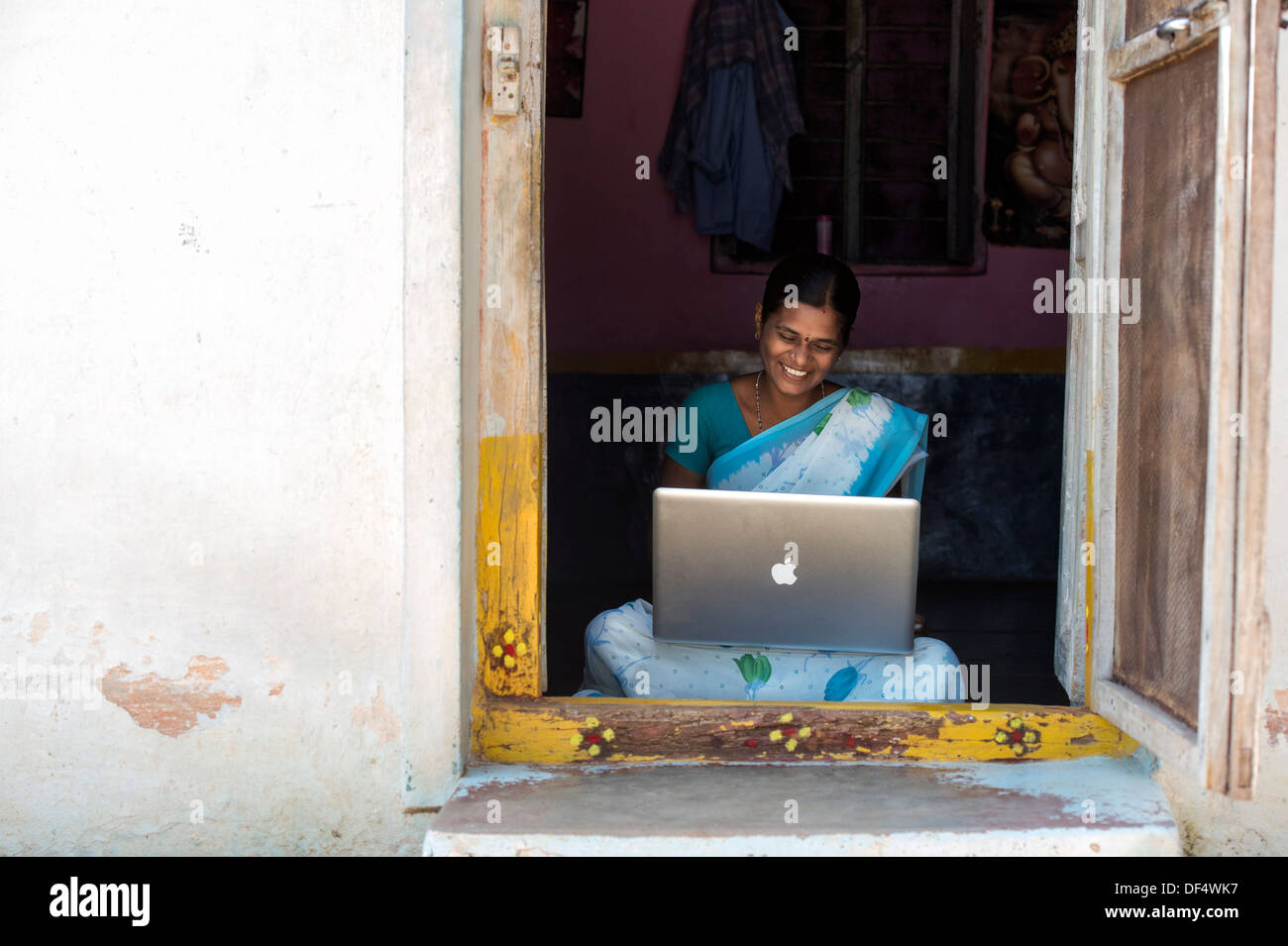 Les femmes du village de l'Inde rurale à la recherche à un portable Apple dans sa maison de la porte. L'Andhra Pradesh, Inde Banque D'Images