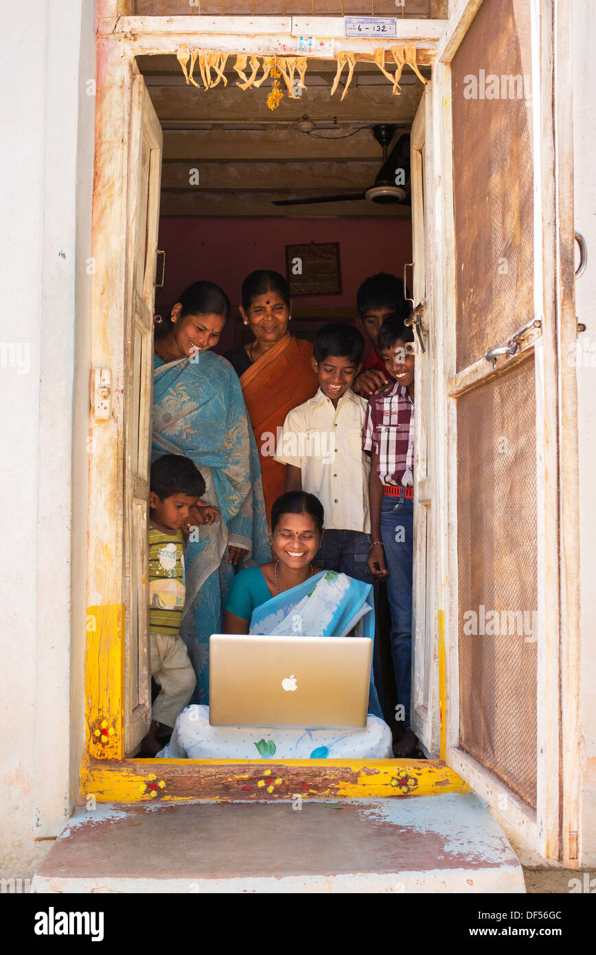 Village de l'Inde rurale et des femmes à la famille à un portable Apple dans sa maison de la porte. L'Andhra Pradesh, Inde Banque D'Images