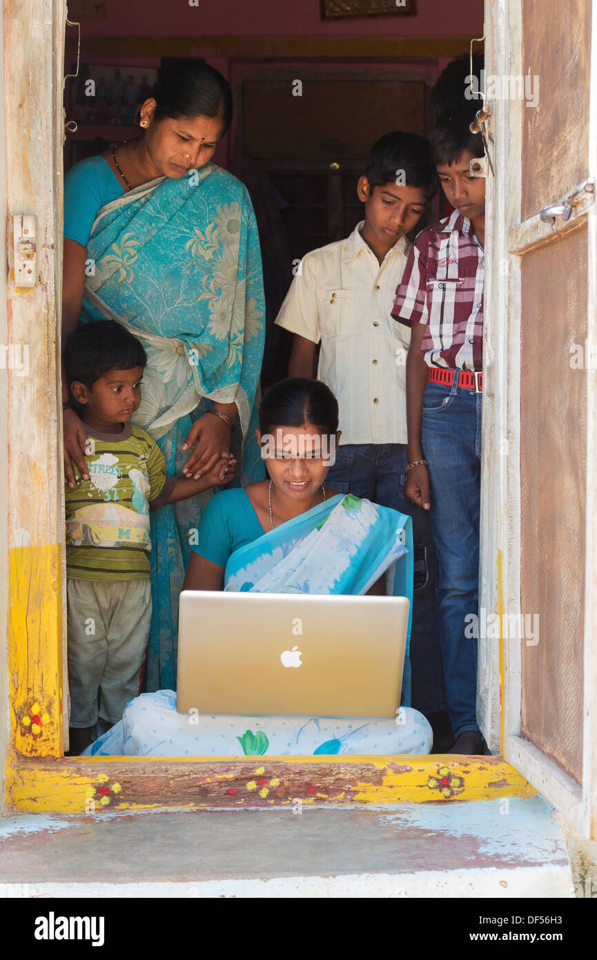 Village de l'Inde rurale et des femmes à la famille à un portable Apple dans sa maison de la porte. L'Andhra Pradesh, Inde Banque D'Images