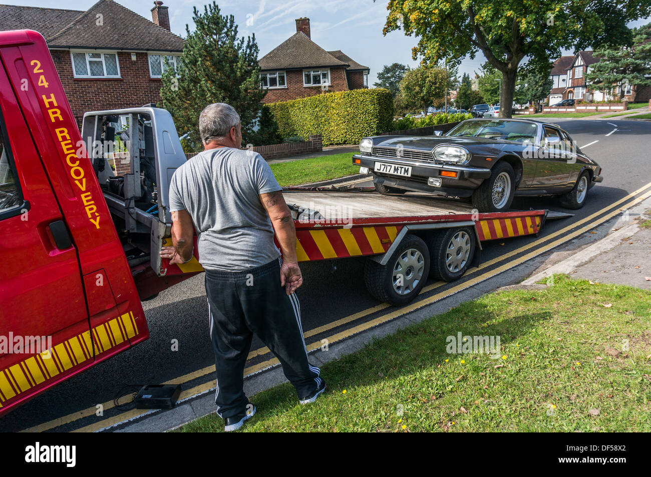 Un treuillage homme Jaguar XJS sur son véhicule de récupération, dans and Banstead, Surrey, Angleterre. Banque D'Images