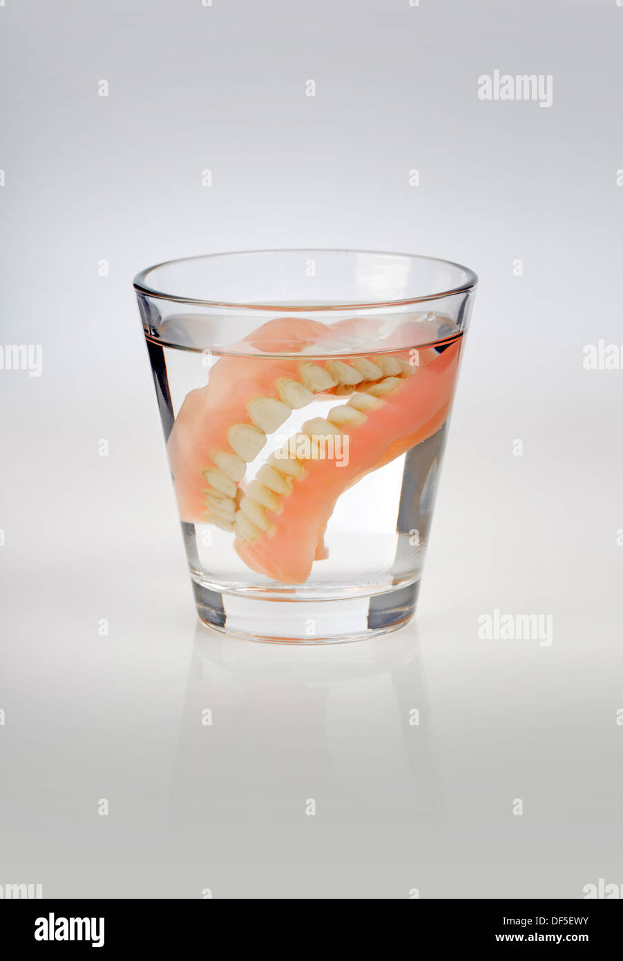 Vieux dentier dans un verre d'eau. Banque D'Images