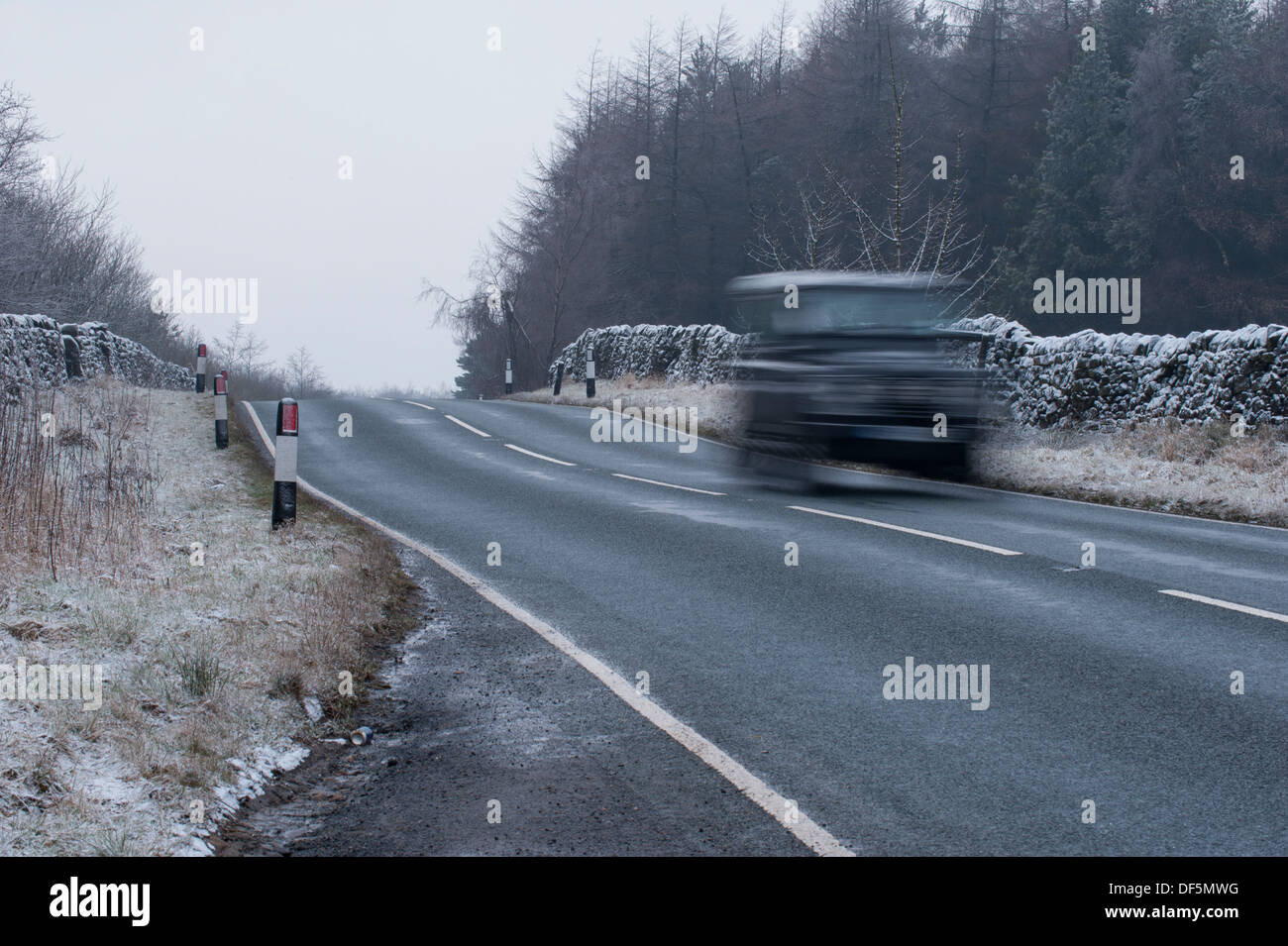 Blurred motion de Land Rover Defender 4x4 voyager & roulage sur country lane sur froid, glaciale, glaciale journée d'hiver - West Yorkshire, Angleterre, Royaume-Uni. Banque D'Images