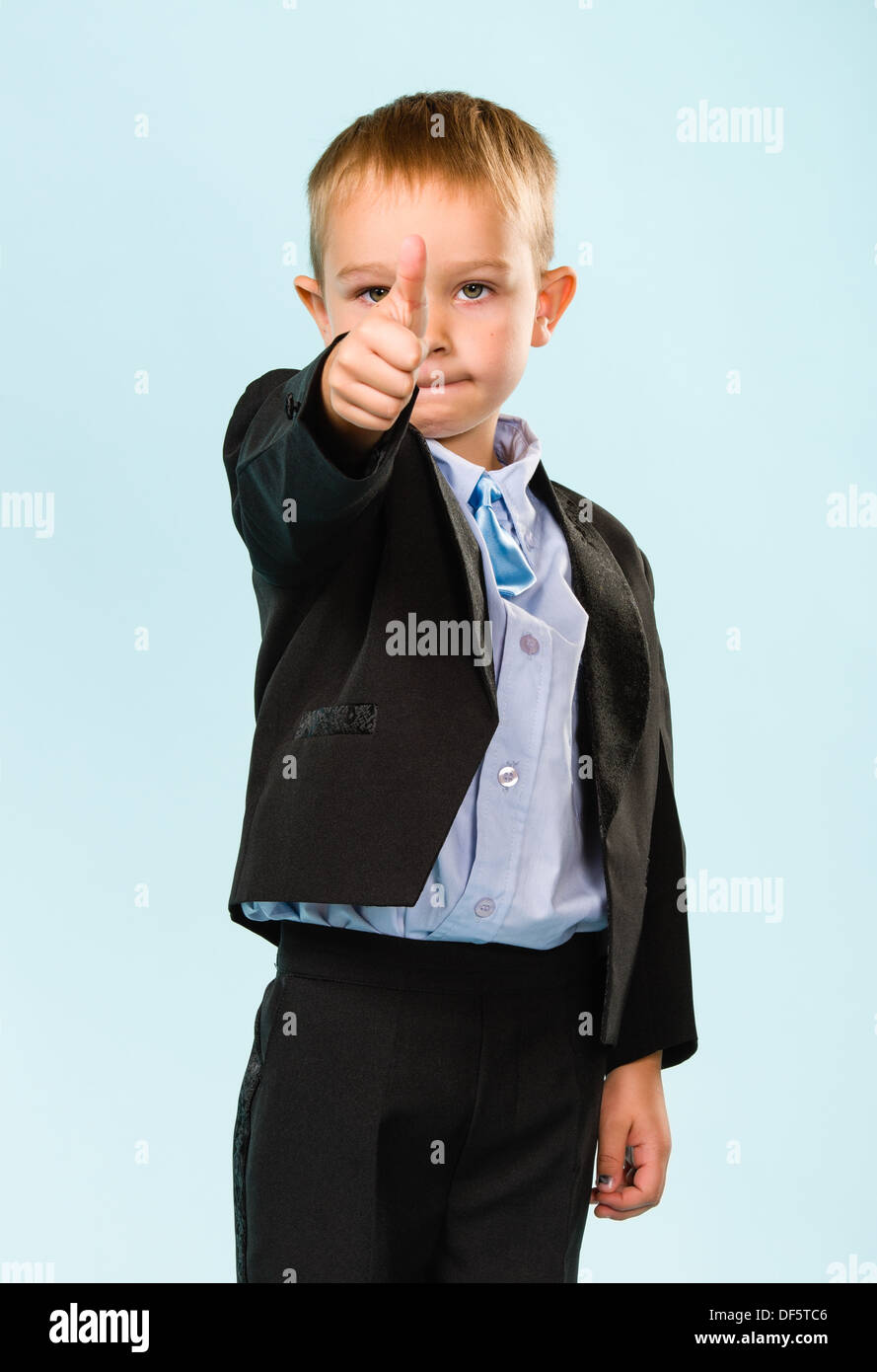 Little Boy wearing costume, Thumbs up, studio shot et fond bleu clair Banque D'Images