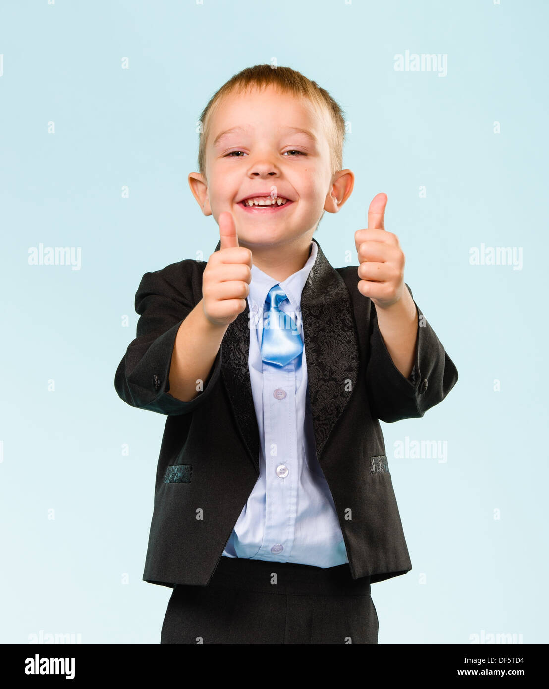 Smiling little boy wearing costume, Thumbs up, studio shot et fond bleu clair Banque D'Images