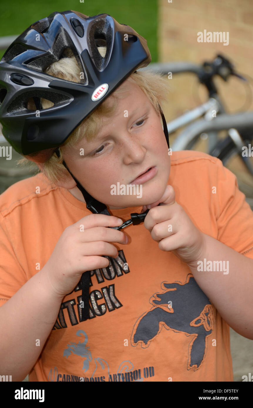 Un jeune garçon lui met un casque de vélo avant de Banque D'Images