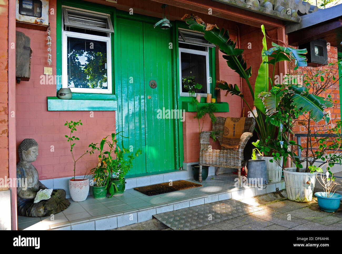 Petite maison en briques avec une porte verte et président de canne Banque D'Images