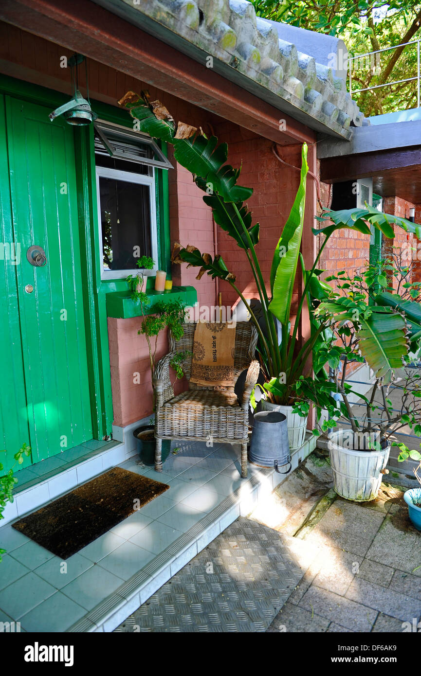 Petite maison en briques avec une porte verte et président de canne Banque D'Images