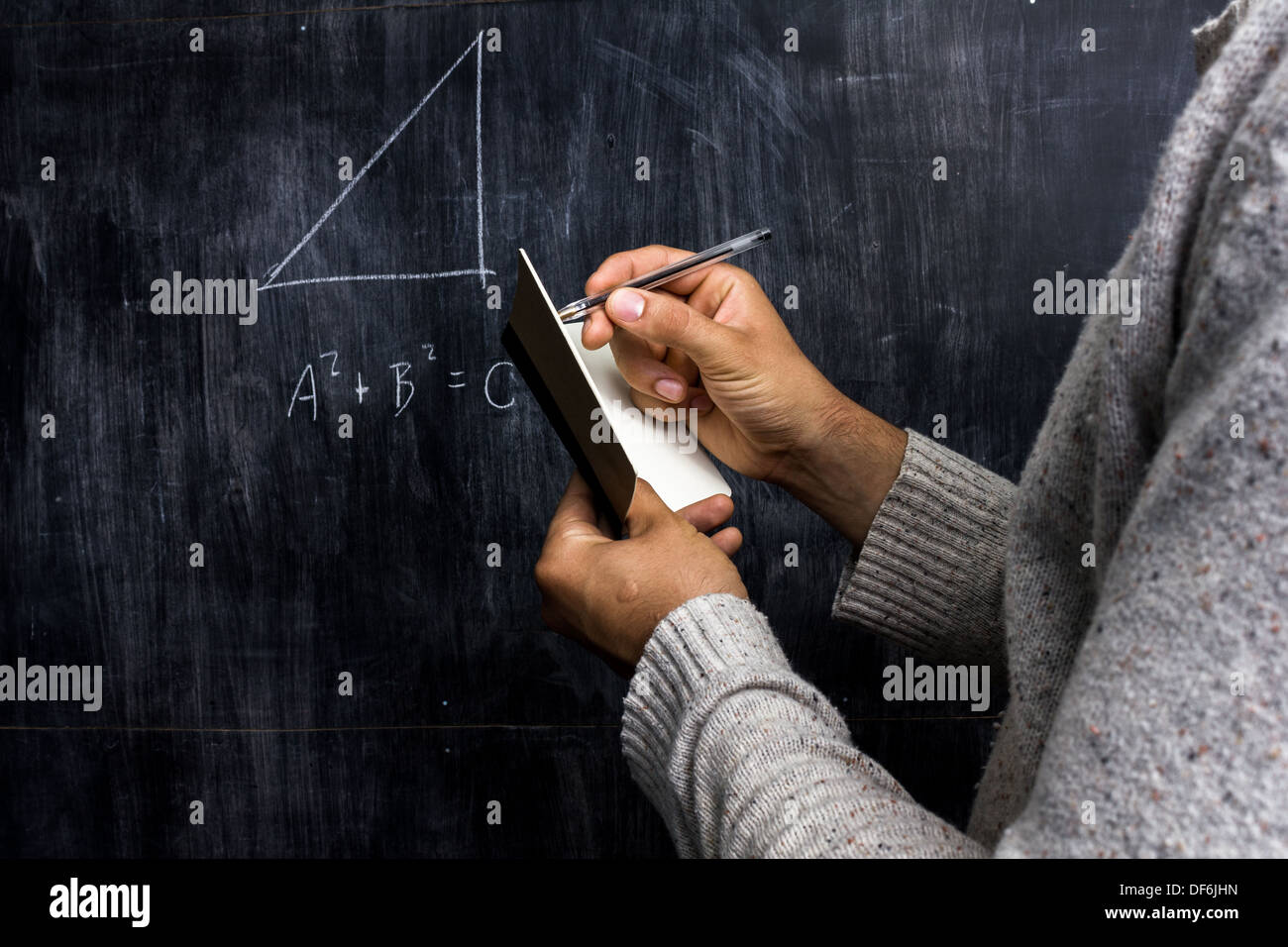 Jeune homme en prenant des notes de formule mathématique sur un tableau noir Banque D'Images