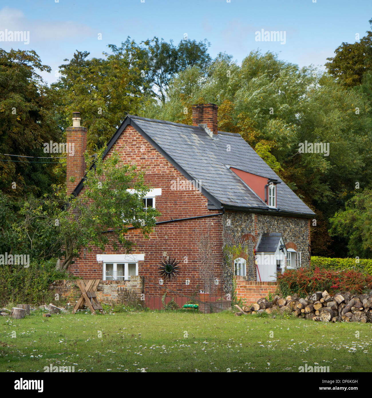 L'extérieur d'un petit cottage en brique isolé dans un champ entouré d'arbres dans le Suffolk, Angleterre. Banque D'Images