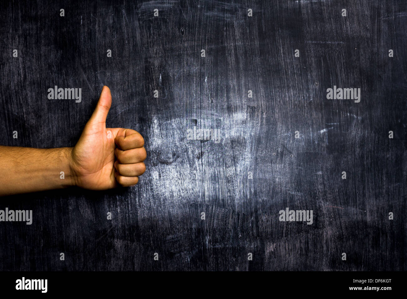La main de l'homme geste giving Thumbs up in front of blackboard Banque D'Images