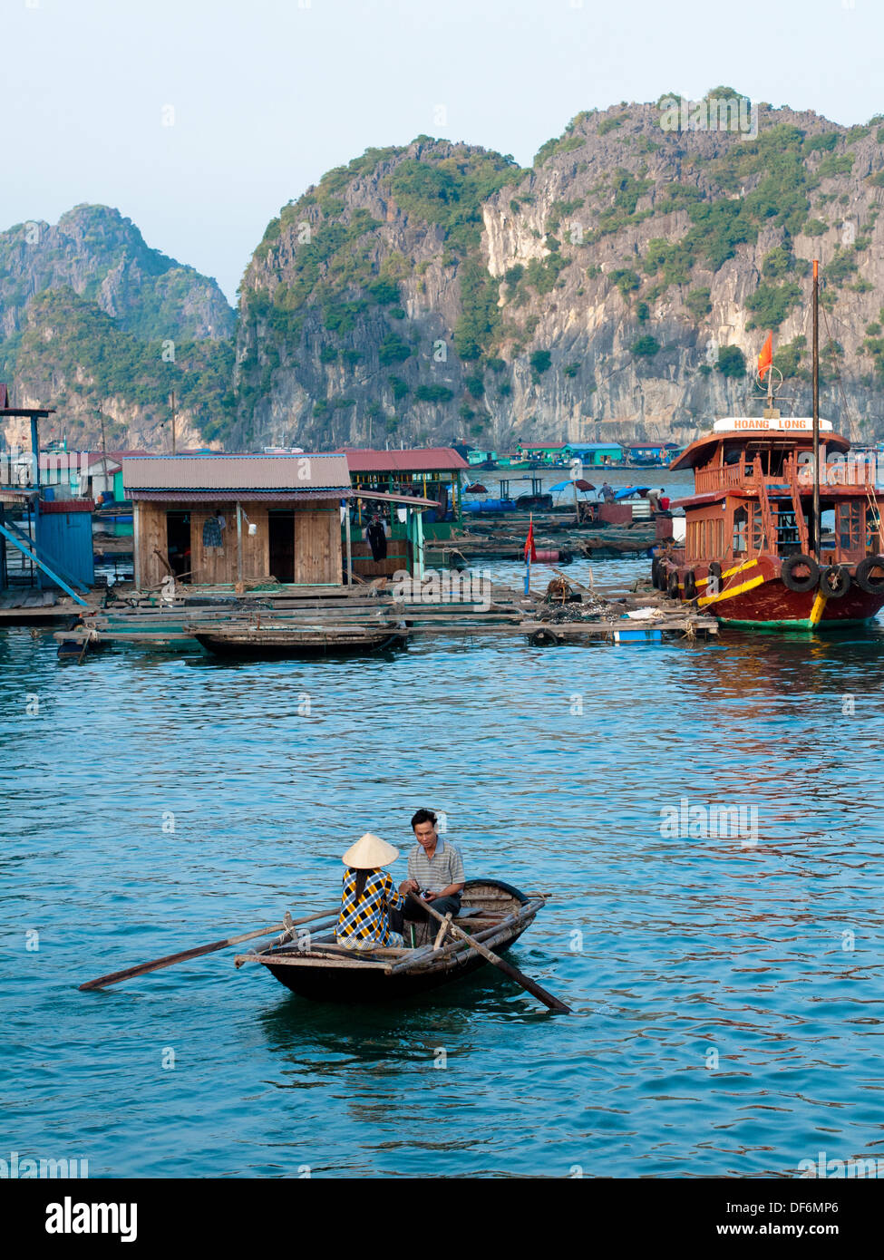 Un vietnamien l'homme et la femme dans une barque près d'un village flottant au large de l'île de Cat Ba dans la baie de Lan Ha, Halong Bay, Vietnam. Banque D'Images