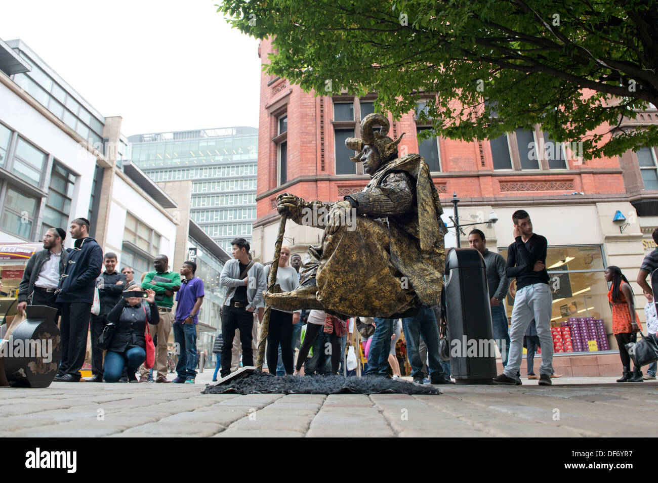 Un artiste de rue effectue sur Market Street dans le centre-ville de Manchester, surveillée par des passants. Banque D'Images