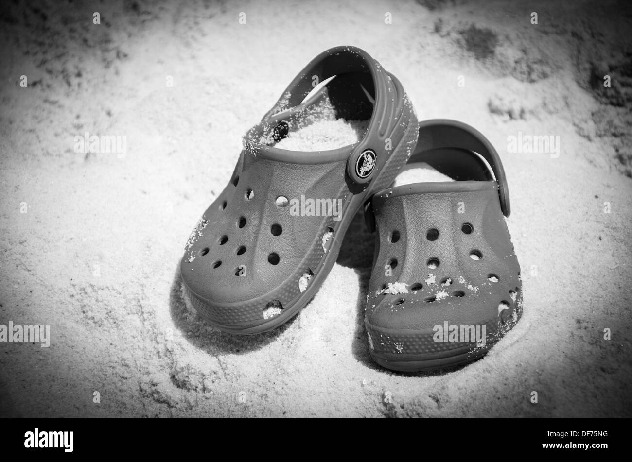 Paire de chaussures Crocs couverts de sable sur la plage Banque D'Images