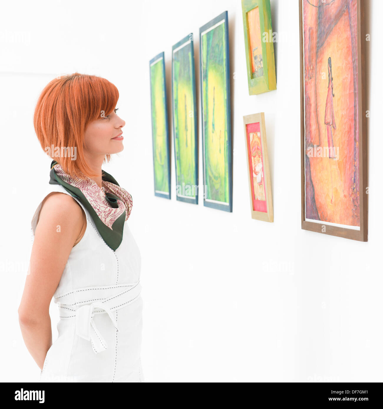 Vue latérale du jeune belle Rousse femme debout dans une galerie d'art en contemplant une œuvre d'art Banque D'Images