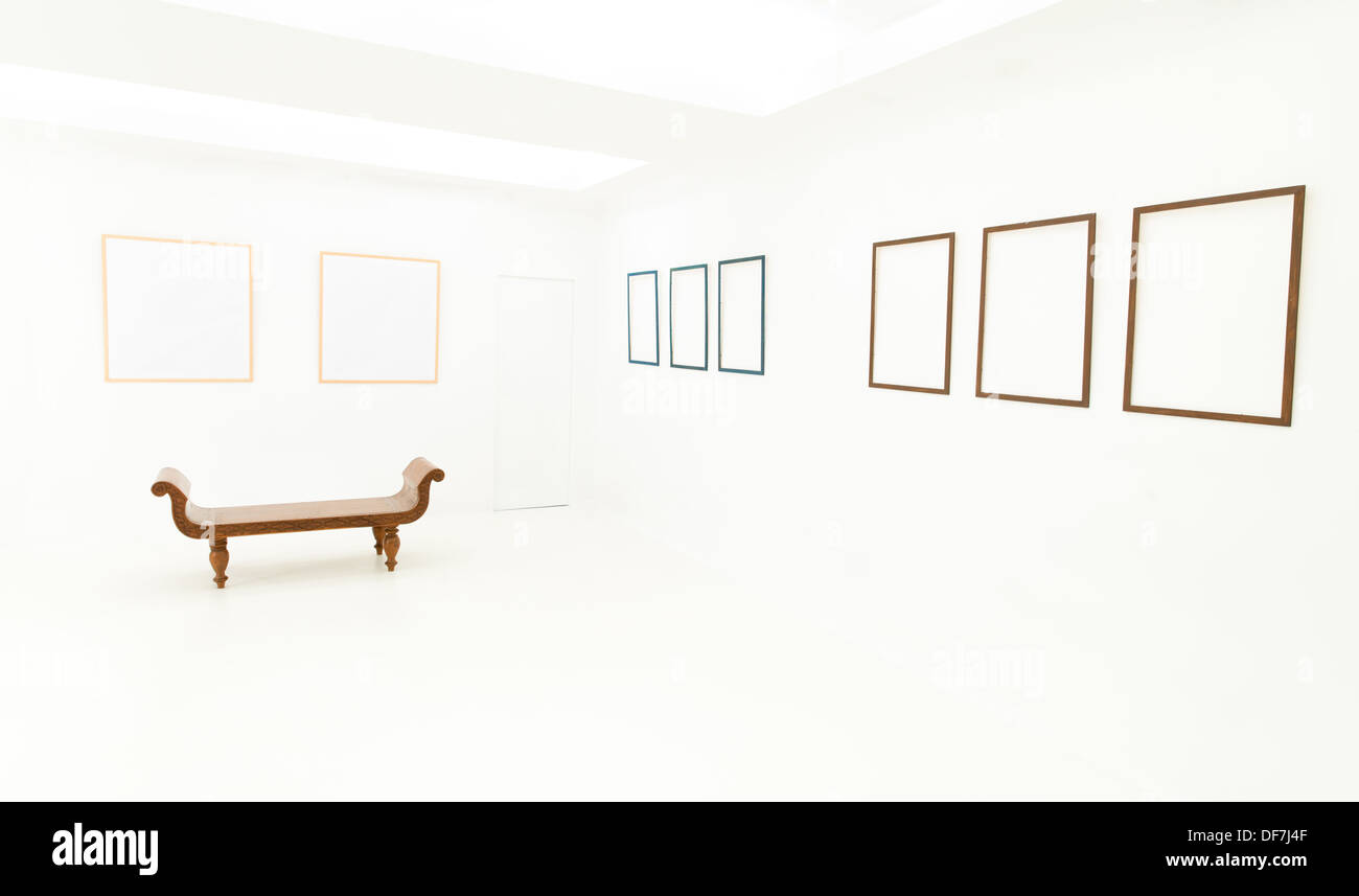 Brown banc en bois placés dans une salle blanche avec des images affichées sur les murs vides Banque D'Images