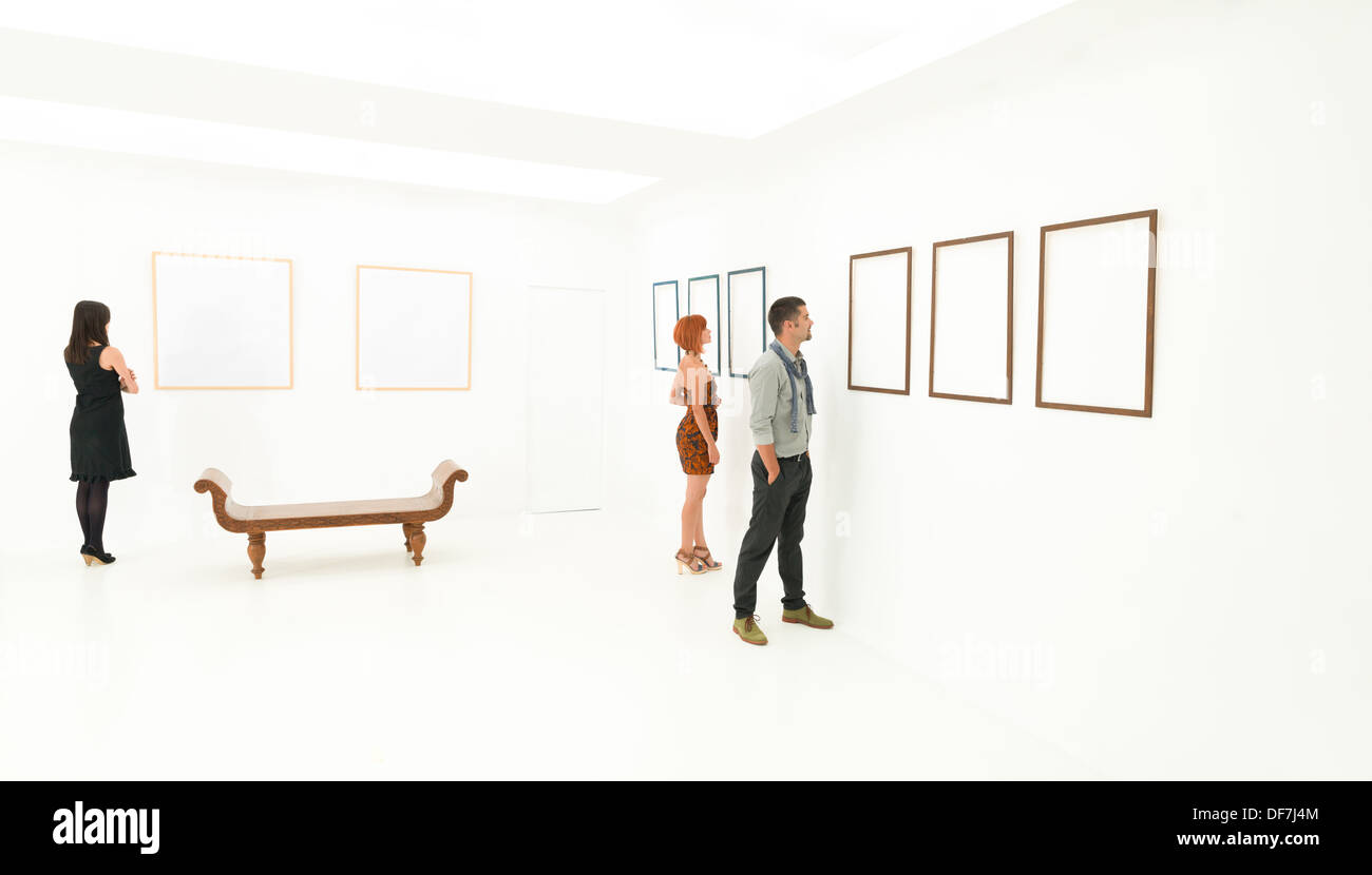 Groupe de trois peuples caucasiens debout dans une chambre à vide à blanc images affichées sur les murs en face d'eux Banque D'Images
