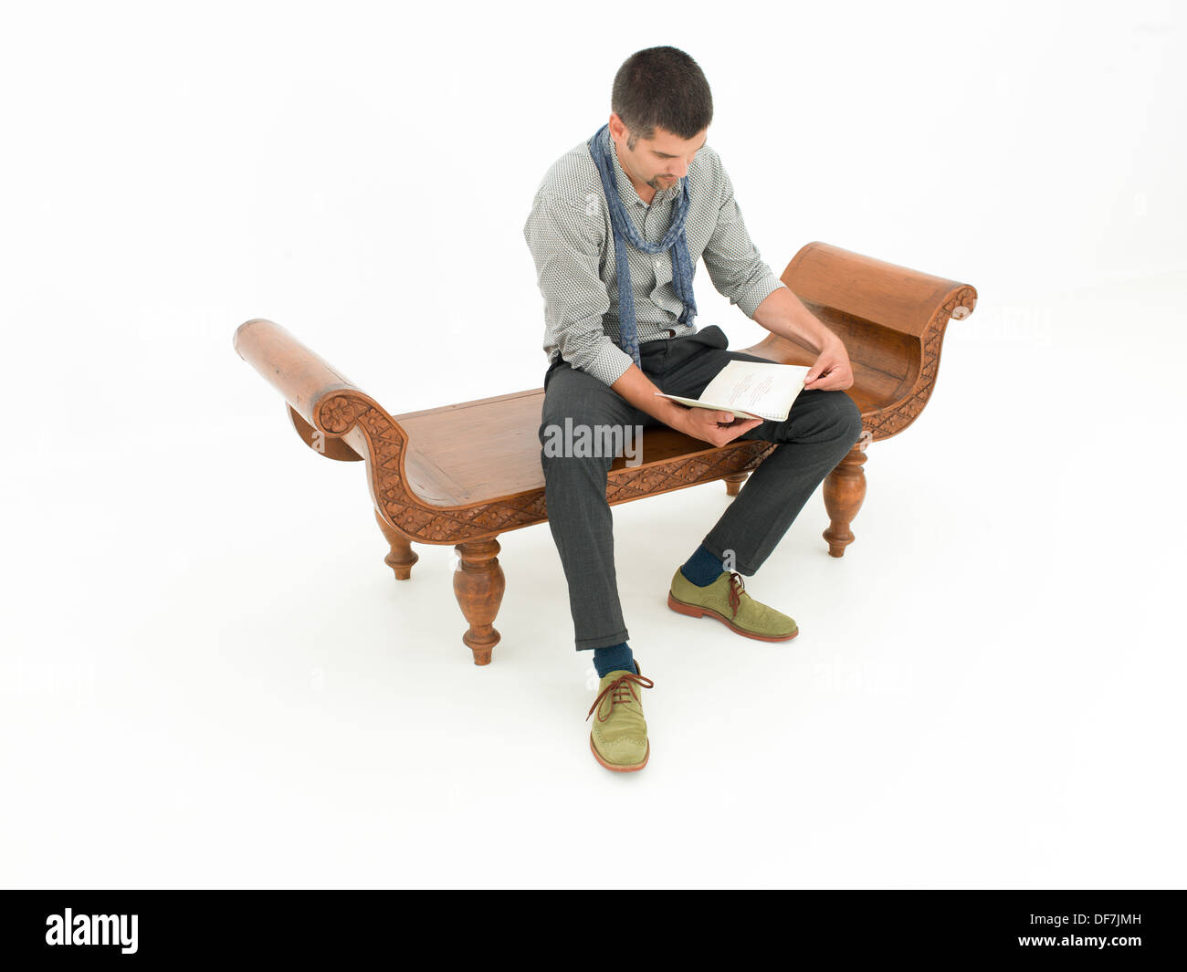 Young caucasian homme assis sur un banc en bois et la lecture d'un livre Banque D'Images