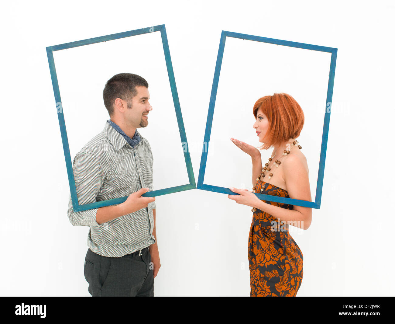 Vue de côté de l'homme et de la femme tenant deux cadres vides et s'embrasser sur fond blanc Banque D'Images