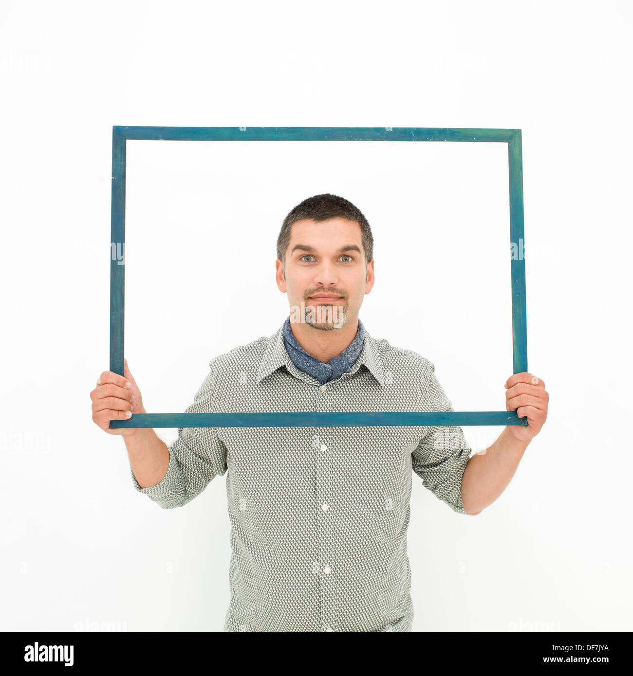 Caucasian man holding un cadre vide en face de lui, sur fond blanc Banque D'Images