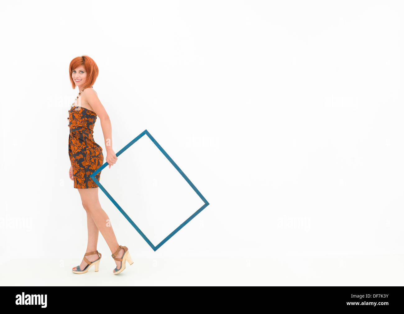 Caucasian woman holding an empty cadre en bois et marche sur fond blanc Banque D'Images